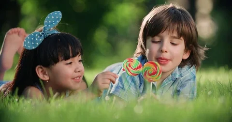 Two small children,Caucasian boy and Asian girl having fun in the Park with a Stock Footage