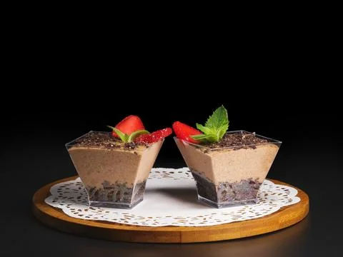 Two small chocolate dessert cups topped with fresh strawberries and mint leav 库存照片