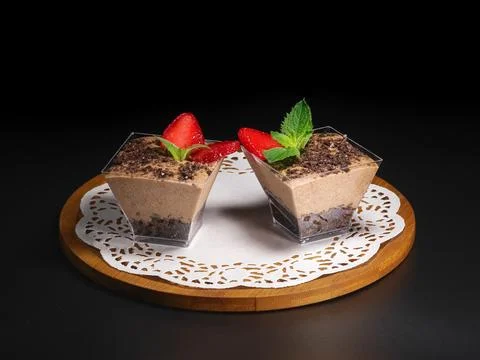Two small chocolate dessert cups topped with fresh strawberries and mint leav Stock Photos