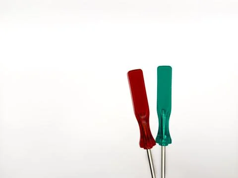 Two small colored plastic screwdrivers on a white background, red and green. Stock Photos