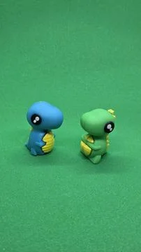 Two small cute blue and green toy dinosaur figures standing on bright green.. Stock Photos