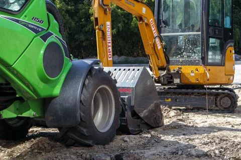 Two small excavators on a large construction site. Bright green on wheels and Fotos Stock