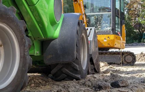 Two small excavators on a large construction site. Bright green on wheels and Stock-Fotos