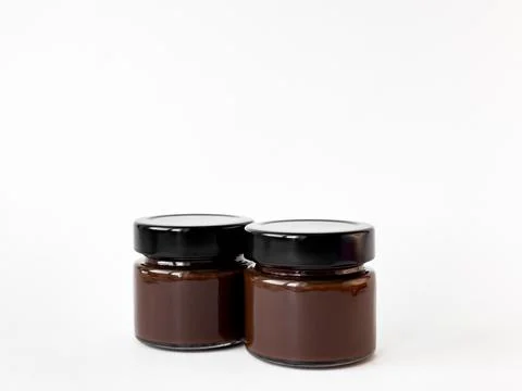 Two small glass jars filled with chocolate spread on a white background Stock-Fotos
