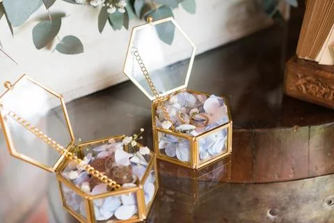 Two small golden boxes with white flowers, coins and wedding rings inside. .. Stock Photos