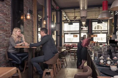 Two small groups of people, couple, coffee shop indoors Stock Photos