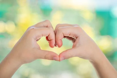 Two small hands forming a heart shape together with soft blurred natural Stock Photos