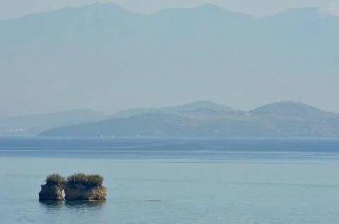 Two small islands covered with bushes in a bay, with mountains in the distance. Stock Photos