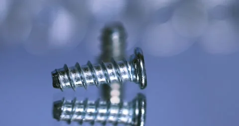 Two small metal screws rolling on blue background close up view. Stock Footage 320204122