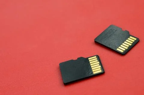 Two small micro SD memory cards lie on a red background. A small and compact  Stock Photos