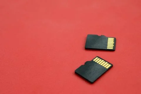 Two small micro SD memory cards lie on a red background. A small and compact  Stock Photos