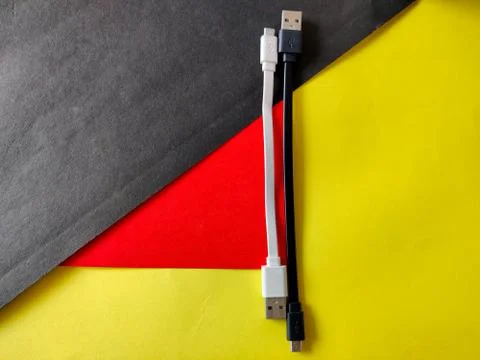 Two small micro USB cables in white and black color. Isolated on yellow and b Stock Photos