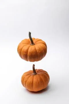 Two small orange pumpkins stacked on white background 库存照片