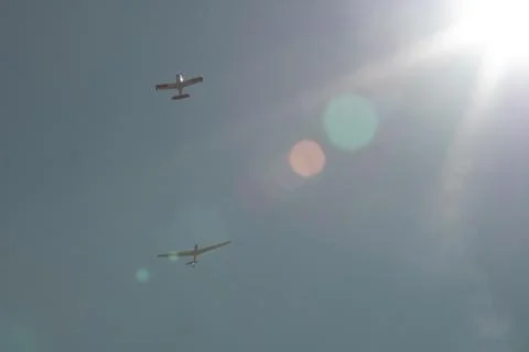 Two small planes flying under the sun Stock Photos
