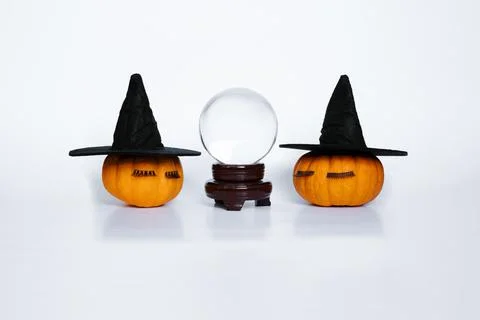Two small pumpkins with witch hats and eyelashes and crystal ball Stock Photos