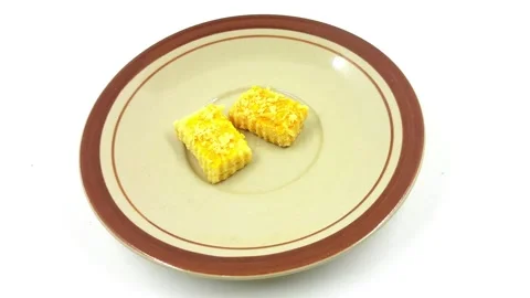 Two small rectangular cheese cookies served simply on a brown rimmed plate 스톡 동영상 328358194