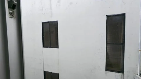 Two small, rectangular windows on a weathered white wall Stock Footage 314090616