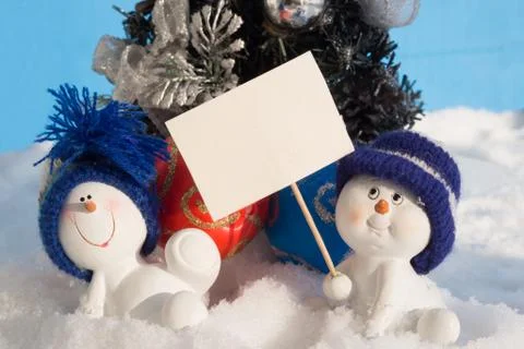 Two small snowman in a cap on snow. Stock Photos