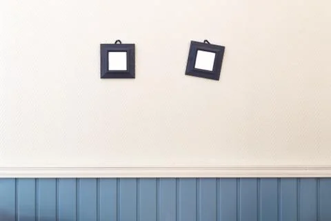 Two small square frames hanging on the white and blue wall Stock Photos
