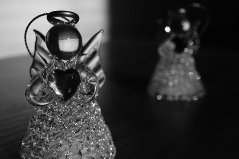 Two small statues of angels on the table, light with dark, black and white ph Photos