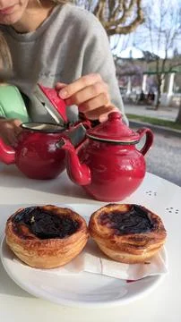 Two small teapots with tea and two national Portuguese cakes on a table in a 写真素材