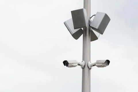 Two small white CCTV cameras and loudspeaker speakers on a pole Stock Photos