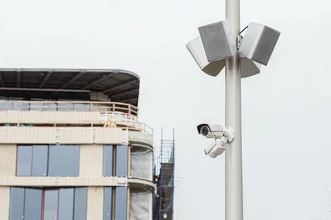 Two small white CCTV cameras and loudspeaker speakers on a pole Foto stock