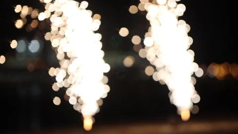 Two small white firework burning and exploding - spreads sparkles on the beach - Stock Footage 133027248