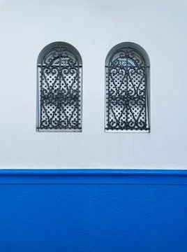 Two small windows protected with metallic railings in the old medina of Asilah Stock Photos