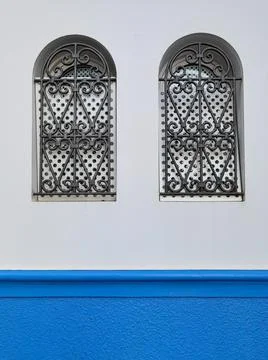 Two small windows protected with metallic railings in the old medina of Asilah Stock Photos