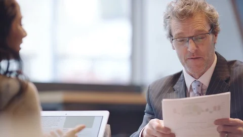 Two smartly dressed business people discussing figures in a coffee shop Stock Footage 87722553