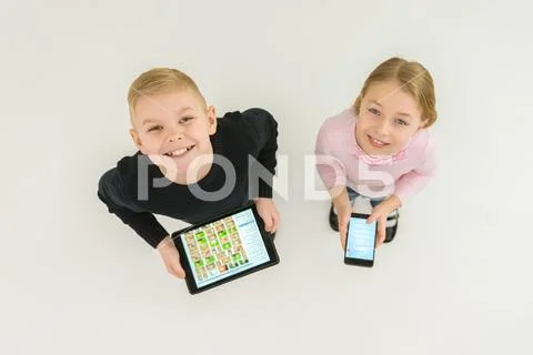 The two smile children stand with devices. View from above Stock Photos