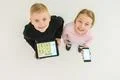 The two smile kids stand with devices. View from above Photo