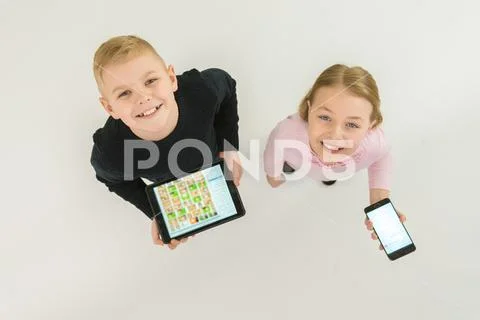 The two smile kids stand with devices. View from above Stock Photos