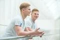 The two smile twin stand near the handrail and gesture Photo