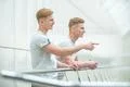 The two smile twin stand on the office balcony and gesture Photo