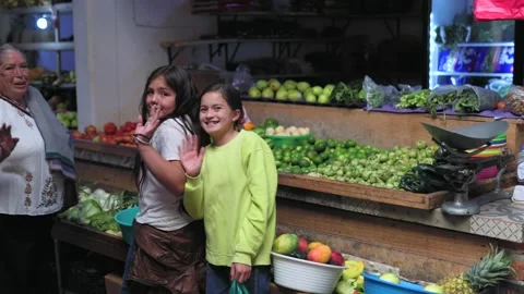 Two smiling children and a friendly elderly grocer waving at a family market in Stock Footage 340598232