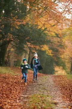 Two Smiling Children Having Fun Running Along Path Through Autumn Woodland Stock Photos