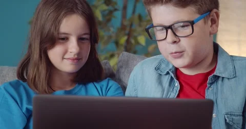 Two smiling children using laptop for fun on sofa Stock-Footage 138407554