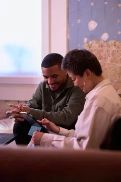 Two smiling colleagues sharing a digital tablet in modern office Stock Photos