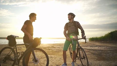 Two smiling cyclists meet each other shake hands seaside dawn slow motion rapid Stock Footage 78061533