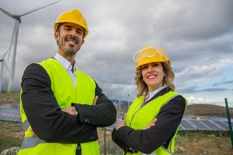 Two smiling engineers with folded arms at a solar power plant Stock Photos