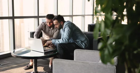 Two smiling friendly workmates working online using laptop Stock Footage 261375382