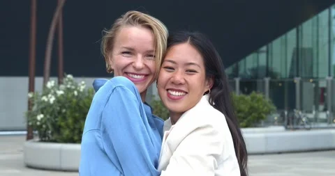 Two smiling multi-ethnic business women embracing looking at camera Stock Footage 220824897