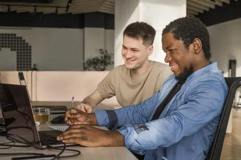 Two smiling positive programmers working in the office of a software development 库存照片