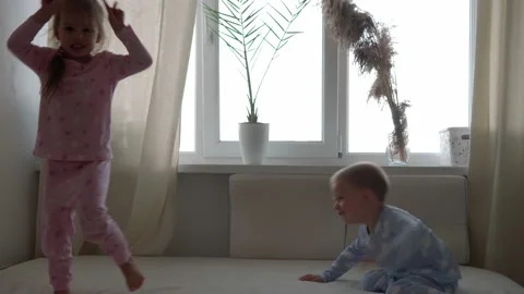 Two smiling preshool, toddler children boy and girl lieing on back in pajamas on Video stock 156057545