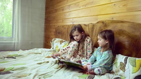 Two smiling preshool, toddler children read large interesting book.in pajamas. Stock Footage 165055349