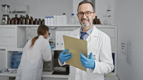 Two smiling scientists standing, arms crossed, reading experiment document .. Stock Footage 268592564