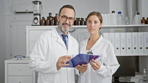 Two smiling scientists together, reading a crucial document on clipboard at.. Stock Footage 262770331