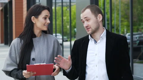 Two smiling smart partners walk on the city street and discussing, reflection gl Stock Footage 199492046